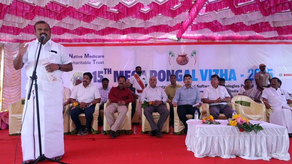 A speaker addressing guests on stage at NMCT's Mega Pongal Vizha 2025