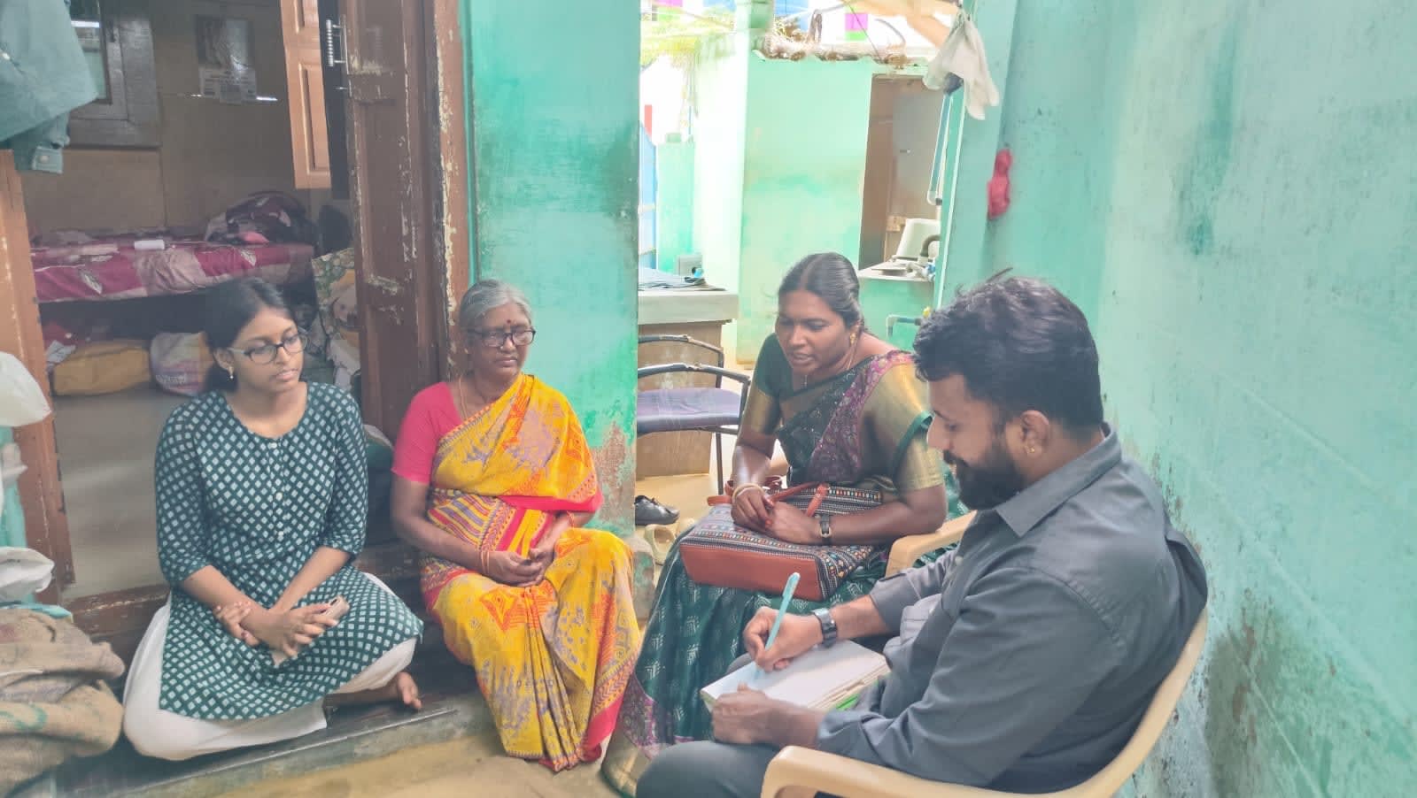 An NMCT staff member taking notes during a home visit with a student and her family
