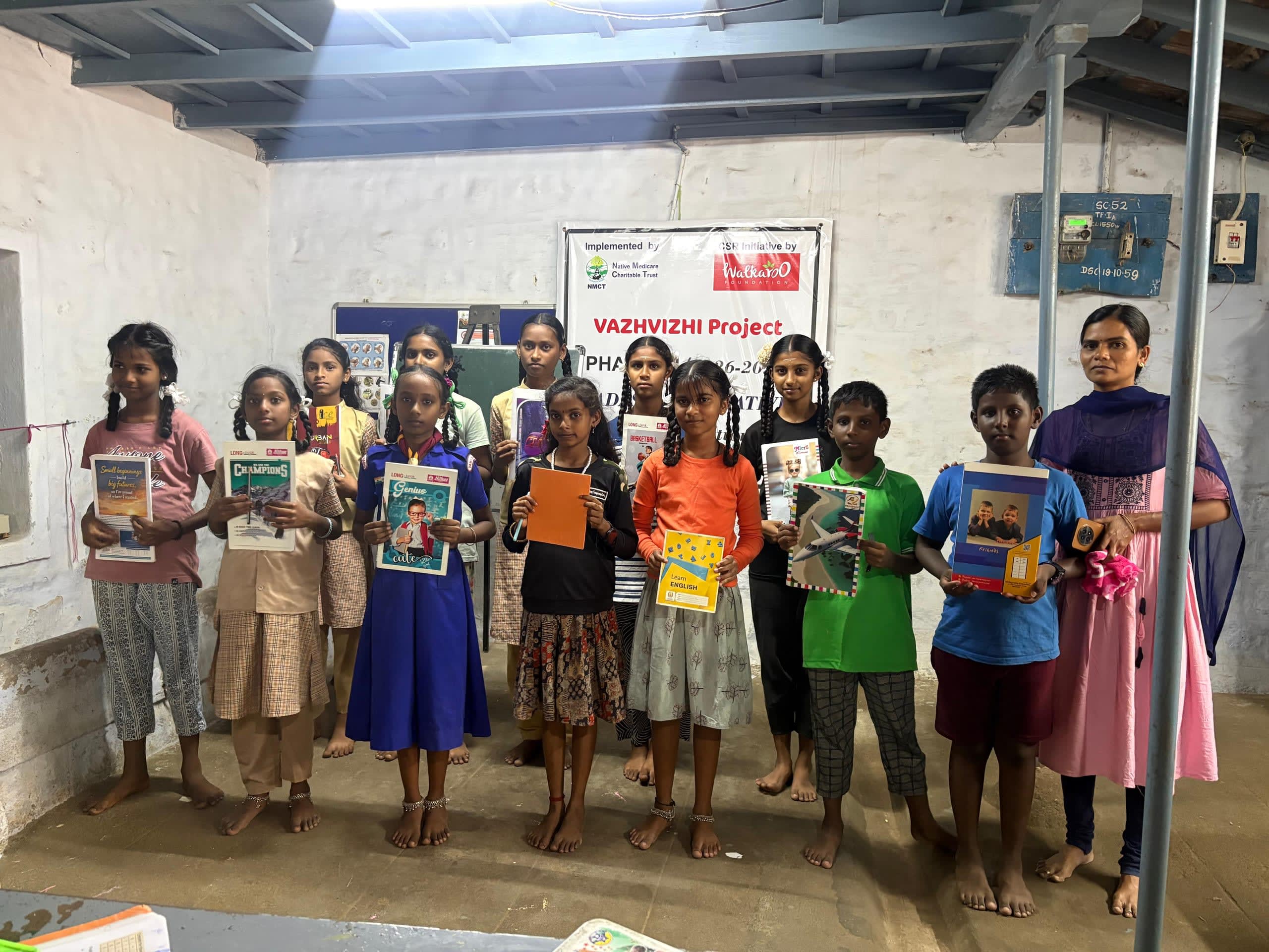 Children holding their books at a Vazhvizhi Project tuition centre, with their teacher