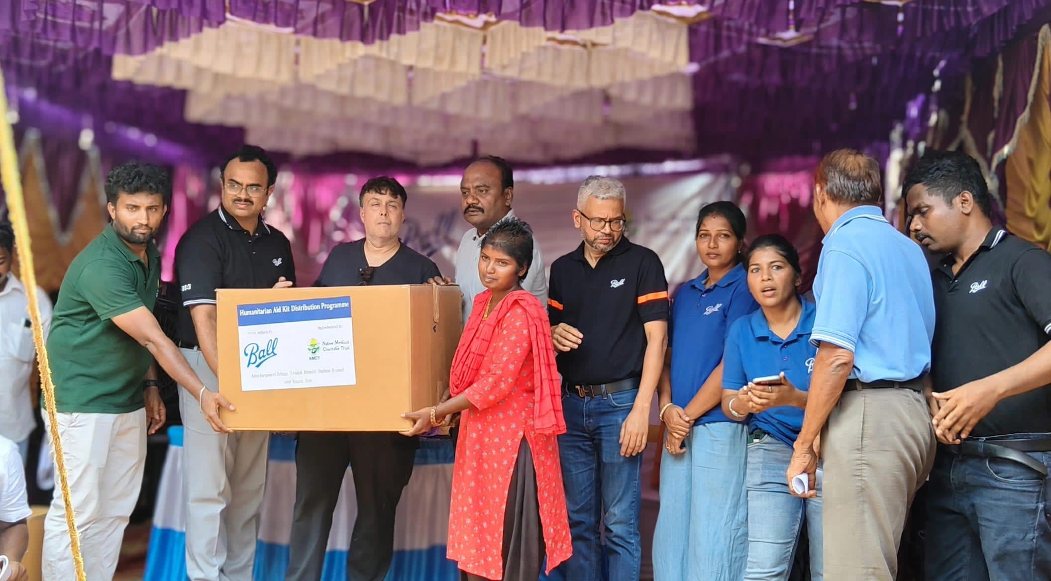 A young woman receives a Humanitarian Aid Kit from Ball and NMCT representatives on stage