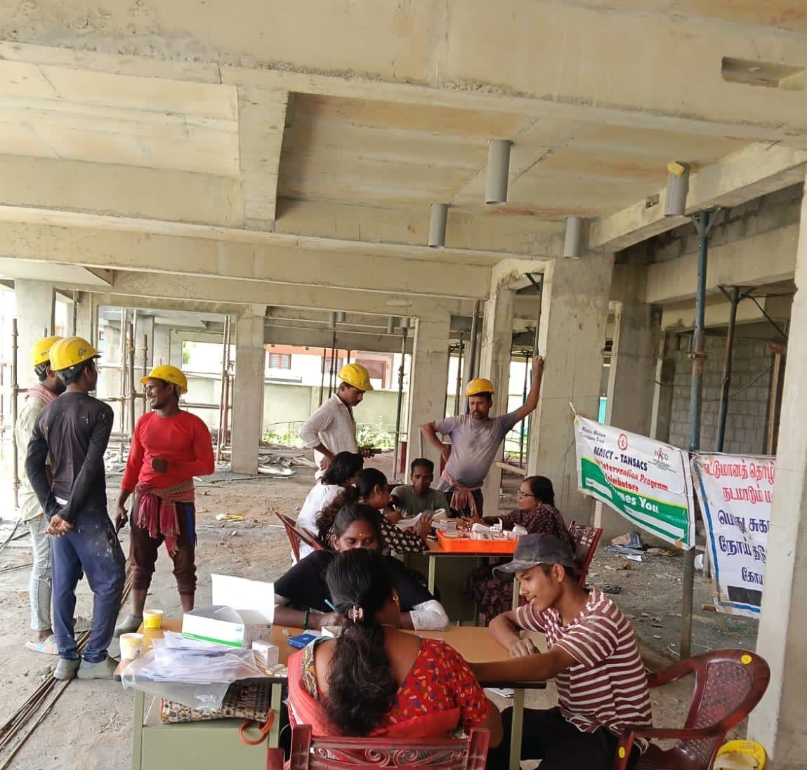 Construction workers at an NMCT and TANSACS health camp set up on a building site