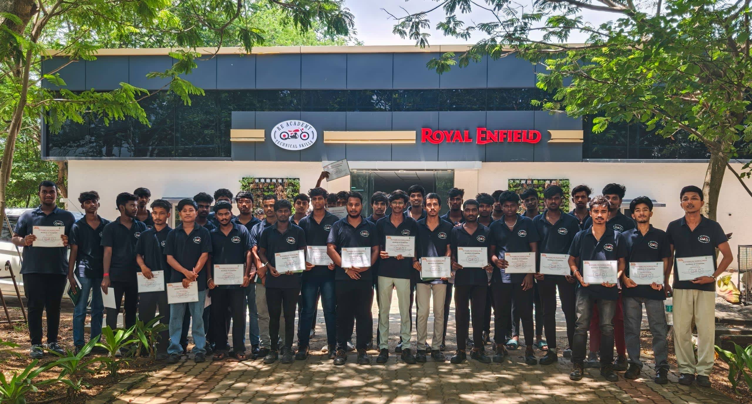 Trainees holding their certificates outside the RE Academy for Technical Skills building